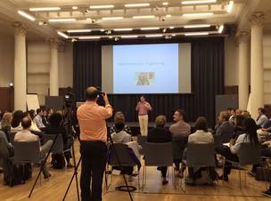 man filming a video of a person talking on a stage